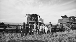 Family posing together in front of farming equipment.